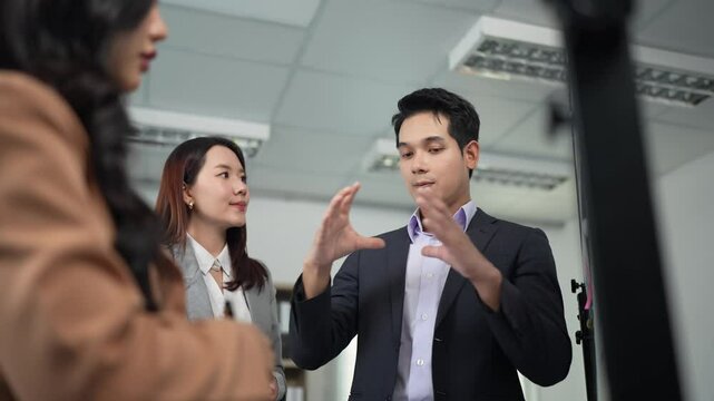 Dynamic professional team collaborating during strategic meeting, sharing innovative project concepts in contemporary corporate workspace with diverse asian business colleagues