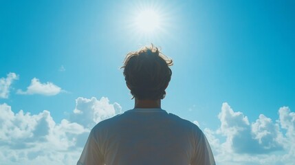 A person gazes upwards at a bright, sunny sky.