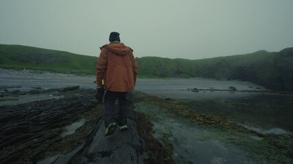 A group of tourists walk along the rocky ocean shore