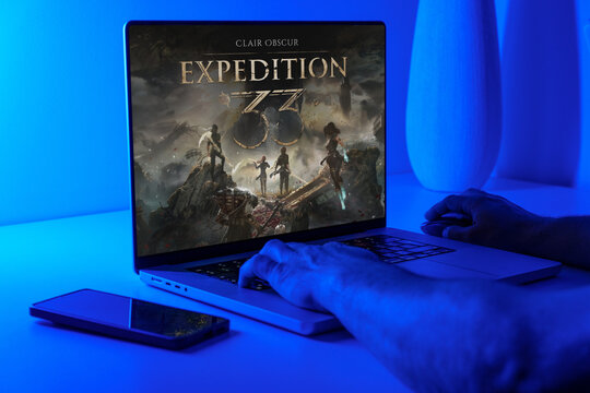 Person playing the video game Clair Obscur: Expedition 33 on a laptop in a dark room