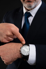 Close-up of businessman pointing at wristwatch.
