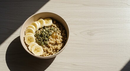 Grain porridge dish with sliced banana and pumpkin seeds. Nutritious morning meal served in bowl for healthy eating habits and mindful consumption on wooden table.