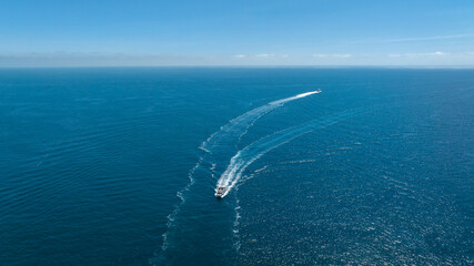 Aerial view of two boats sailing in the blue sea. The view extends to the horizon.