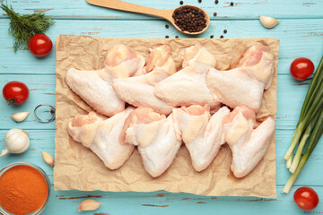 Raw chicken wings with ingredients for cooking on wooden cutting board on blue wooden