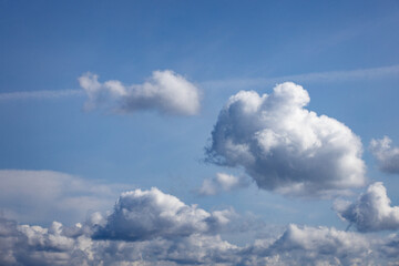 White dreamlike puffy clouds floating in a vast blue sky.