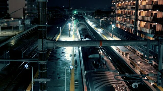日本の地方都市　雨の夜の駅から電車が発車していく
