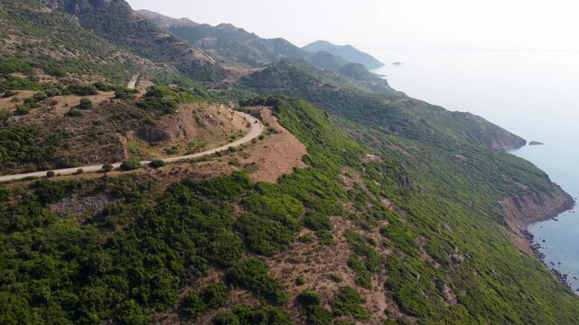 Drone view of a winding road through Grifone Nature Reserve between Bosa and Alghero, next to the sea on the west of Sardinia, Italy