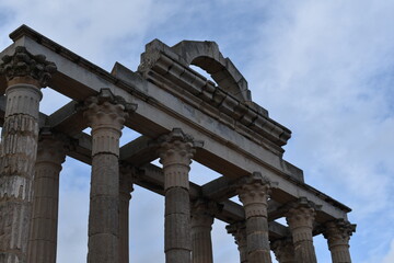 Fototapeta premium Close-up view of ancient Roman temple columns and arch in Mérida, highlighting intricate architectural details under a partly cloudy sky 