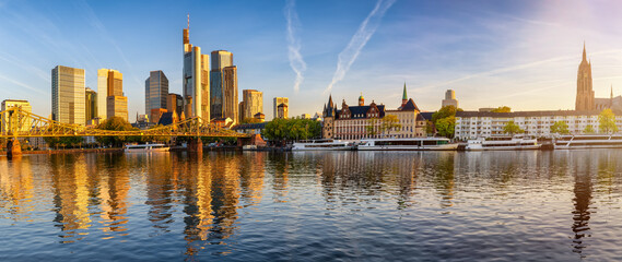 Panoramic view of the skyline of Frankfurt am Main, Germany, with Eiserner Steg bridge, office skyscrapers and Kaiserdom church during a golden sunrise