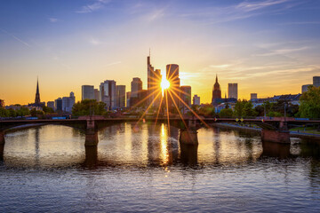 Sunset view of the modern skyline of Frankfurt, Germany, with the sun setting exactly behind the...