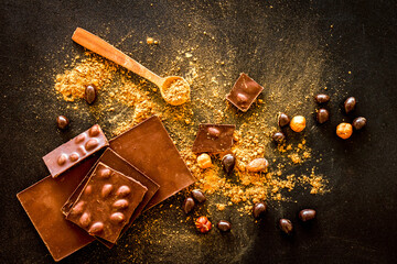 Different variety of chocolate and hazelnut on black background top view