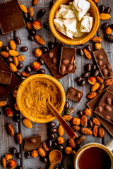 Tea with homemade chocolate bars, nuts, coffee beans on wooden background top view