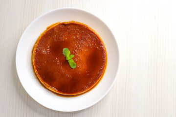 Delicious caramel custard with a glossy caramel top, served on a white plate. Perfectly lit, smooth texture, and minimal background. ideal for menus, blogs, packaging, or dessert features. Copy space