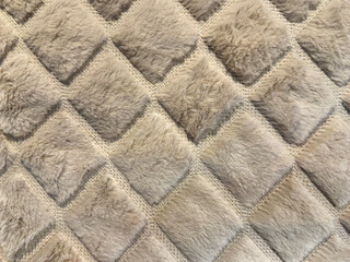Close up of carpet rug in 3d diamond pattern, with fur and light pale white or beige color. Seamless fabric and carpet rug background texture