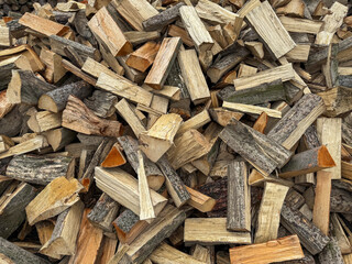Stack of split firewood logs with bark, ready for burning or storage. Close-up of hardwood chopped timber pieces for heating or fireplace.