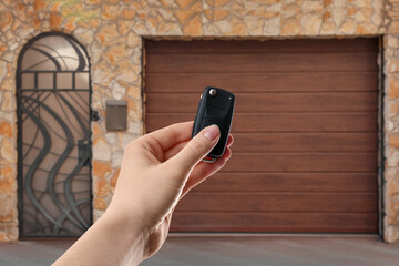 Woman using remote to control electric gate outdoors, closeup