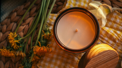 Flat lay of a cup of tea, candle, and fresh spring flowers on a yellow gingham cloth in warm sunlight. Cozy and bright morning mood with natural textures and soft details