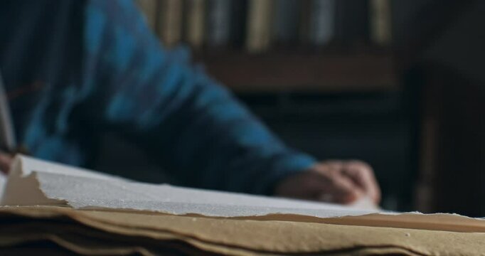 Super Slow Motion of Handmade Paper Sheet Being Carefully Handled on a Wooden Surface, Showcasing Its Texture, Deckled Edges, and Natural Imperfections in a Craft or Artistic Studio Environment.