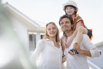 Family fun time with mom and dad at home. Couple playing with their daughter and creating happy childhood memories. Dad carrying his daughter on his shoulders and standing next to mom.