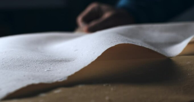 Super Slow Motion Macro of Handmade Paper Sheet Being Carefully Handled on a Wooden Surface, Showcasing Its Texture, Deckled Edges, and Natural Imperfections in a Craft or Artistic Studio Environment.