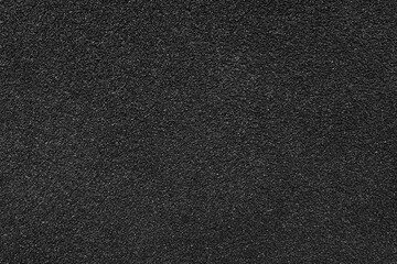 Grainy texture of asphalt, plaster, cement, plastic, rock, stone close up, macro. Background of black colored granular wall surface, rough backdrop