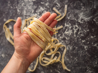 Holding a bunch of pasta over a dark kitchen counter with more pasta in the background. 