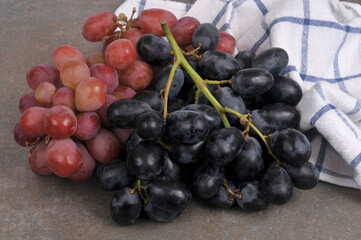 Grappe de raisin rouge et grappe de raisin noir avec un torchon sur fond gris