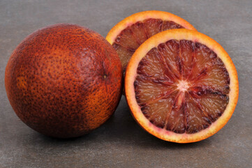 Orange sanguine entière et orange sanguine coupée en deux en gros plan isolées sur fond gris