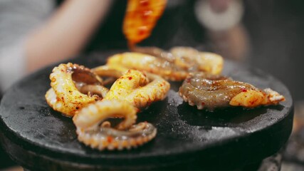 Sizzling seared marinated squid on a hot stone plate. This close-up stock video captures tantalizing aromas and vibrant textures of gourmet cuisine