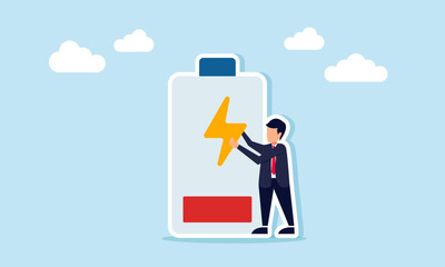Businessman standing next to a low battery holding an electricity icon, illustration of the need to recharge resources for business and production or work systems