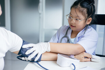 Girl in doctor's uniform examining a patient at a table, Concept Education