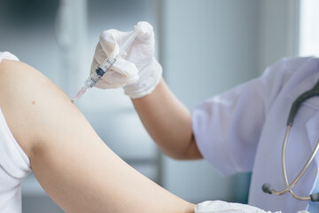 Close-up of a doctor's hand reaching for a syringe to inject into a patient's shoulde