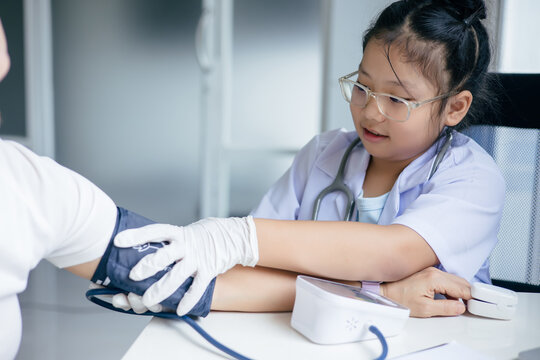 Girl in doctor's uniform examining a patient at a table, Concept Education - Powered by Adobe