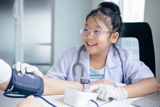 Girl in doctor's uniform examining a patient at a table, Concept Education