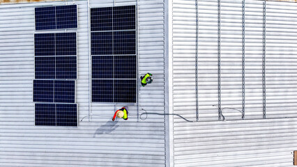 A sustainable energy project featuring solar panels on a roof surrounded by tropical trees,...