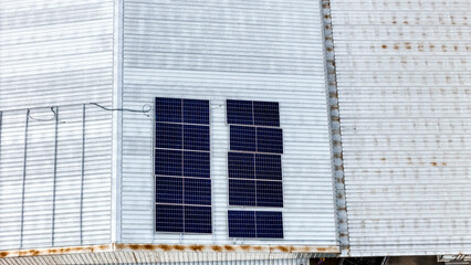 A sustainable energy project featuring solar panels on a roof surrounded by tropical trees,...