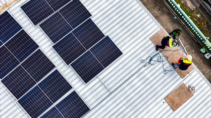 A sustainable energy project featuring solar panels on a roof surrounded by tropical trees,...