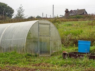 Old greenhouse in a field on a cloudy day