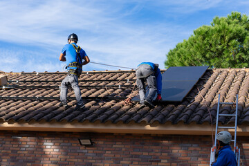 Workers installing solar panel on a roof of residential building