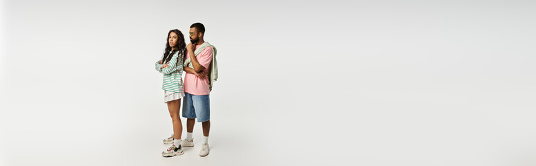 Stylish couple showcasing contemporary fashion against a clean, minimalistic backdrop