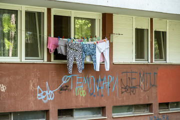 Wäscheleine vor Wohnhaus mit Graffiti und offenen Fenstern