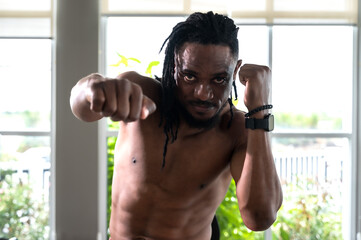 Portrait strong muscular black muay thai boxer guarding up training in gym