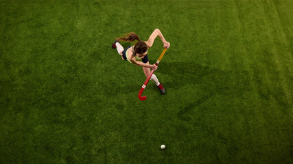 High angle view of athlete approaching ball on green grass field against white studio background,...