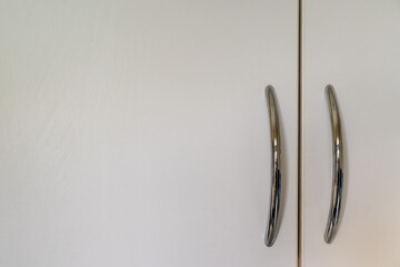 White cupboard doors with silver-colored handles positioned to the right. Copy space to left.