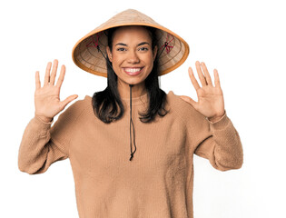 Young Filipina with Vietnamese hat showing number ten with hands.
