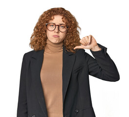 Young Caucasian redhead in business attire showing a dislike gesture, thumbs down. Disagreement...