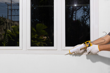 Handyman using acrylic sealant caulk the outside window frame..