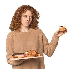 Young Caucasian redhead woman with pastries tray