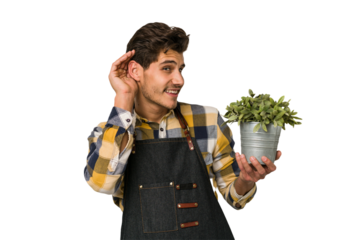 Young caucasian gardener man isolated on white background trying to listening a gossip.