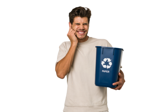 Young caucasian man holding a paper trash for recycle covering ears with hands.